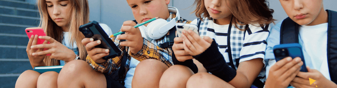dzieci siedzą obok siebie i wpatrują się w ekrany smartfonów
